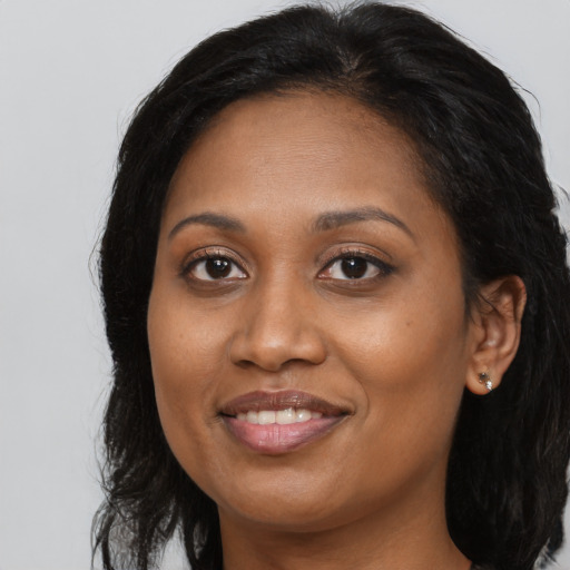 Joyful black young-adult female with long  brown hair and brown eyes