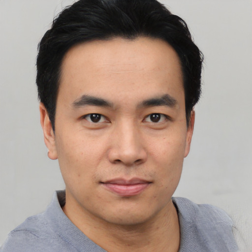 Joyful asian young-adult male with short  black hair and brown eyes