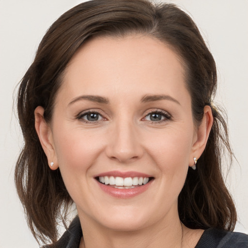 Joyful white young-adult female with medium  brown hair and grey eyes