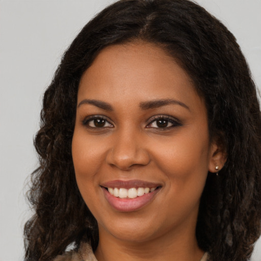 Joyful black young-adult female with long  brown hair and brown eyes