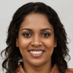 Joyful black young-adult female with long  brown hair and brown eyes