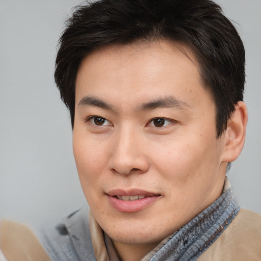 Joyful asian young-adult male with short  brown hair and brown eyes