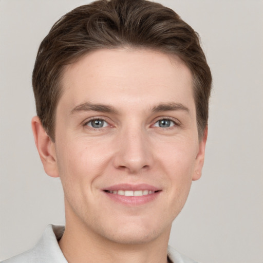 Joyful white young-adult male with short  brown hair and grey eyes