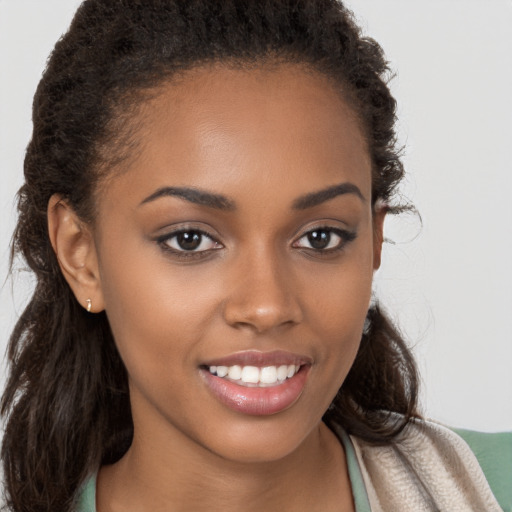 Joyful black young-adult female with long  brown hair and brown eyes