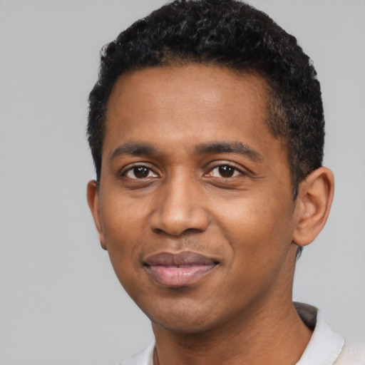 Joyful black young-adult male with short  black hair and brown eyes