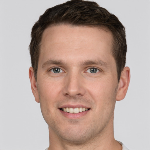 Joyful white young-adult male with short  brown hair and grey eyes