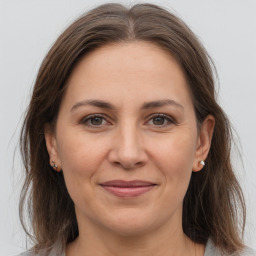 Joyful white adult female with medium  brown hair and grey eyes