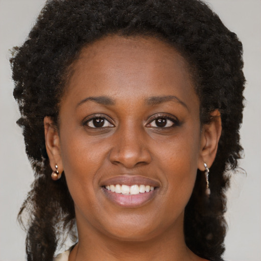 Joyful black young-adult female with long  brown hair and brown eyes