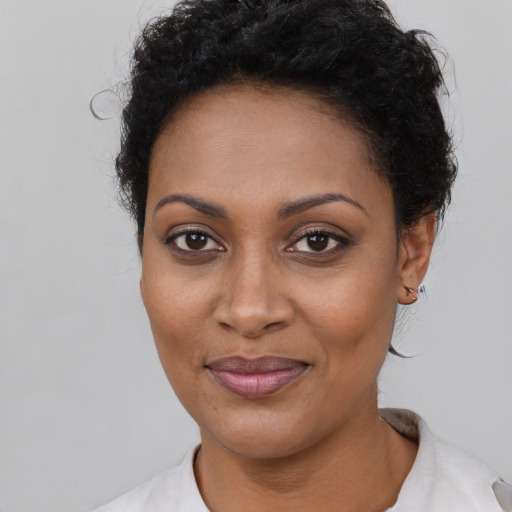 Joyful black young-adult female with short  black hair and brown eyes