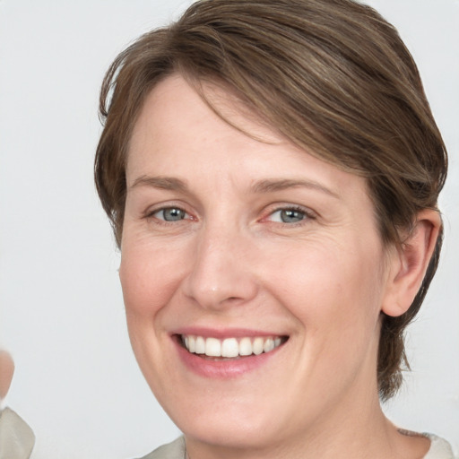 Joyful white young-adult female with medium  brown hair and grey eyes