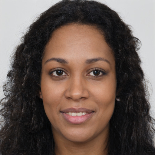 Joyful black young-adult female with long  brown hair and brown eyes