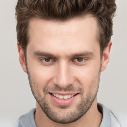 Joyful white young-adult male with short  brown hair and grey eyes