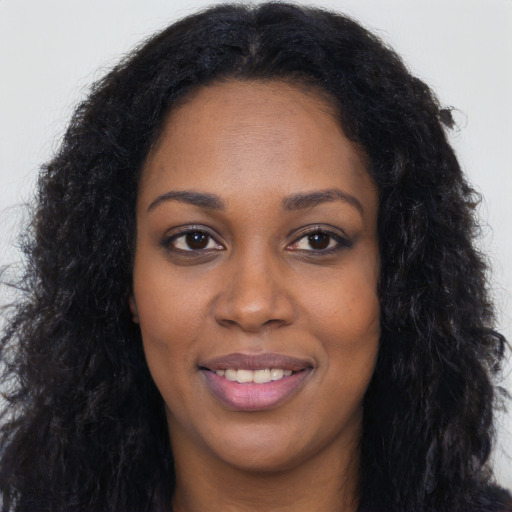 Joyful black young-adult female with long  black hair and brown eyes
