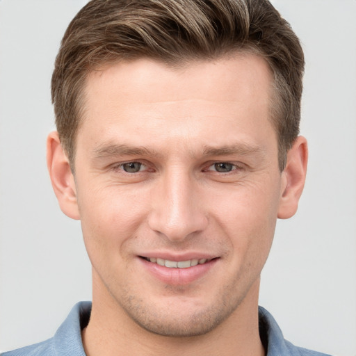 Joyful white young-adult male with short  brown hair and grey eyes