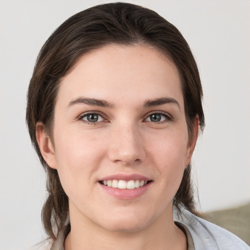 Joyful white young-adult female with medium  brown hair and grey eyes