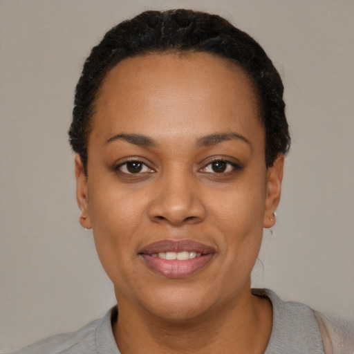 Joyful black young-adult female with short  black hair and brown eyes