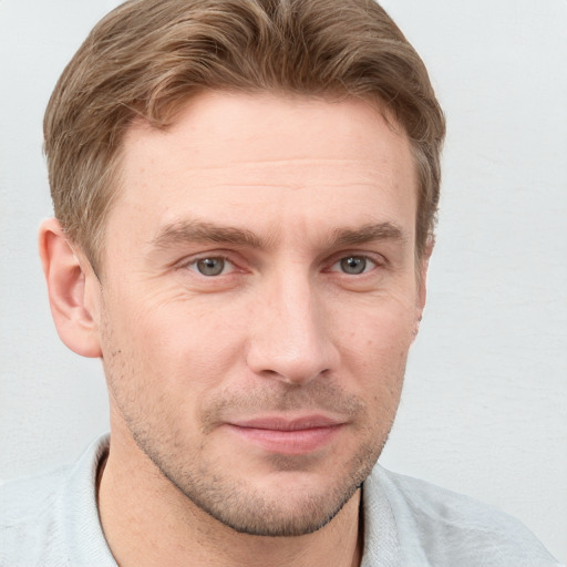 Joyful white young-adult male with short  brown hair and grey eyes