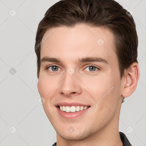 Joyful white young-adult male with short  brown hair and grey eyes