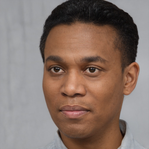 Joyful black young-adult male with short  black hair and brown eyes