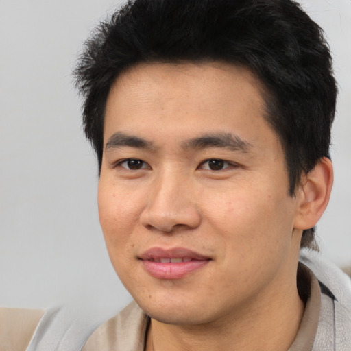 Joyful asian young-adult male with short  brown hair and brown eyes