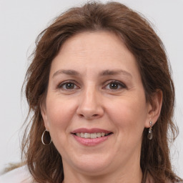 Joyful white adult female with long  brown hair and grey eyes