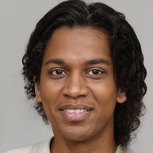 Joyful black adult male with medium  black hair and brown eyes