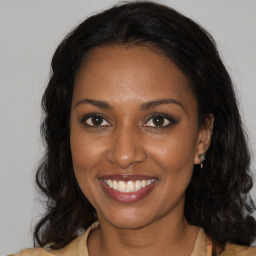 Joyful black young-adult female with long  brown hair and brown eyes