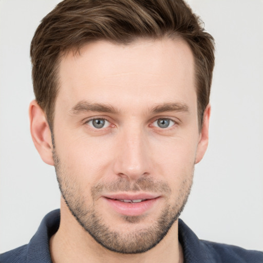 Joyful white young-adult male with short  brown hair and grey eyes