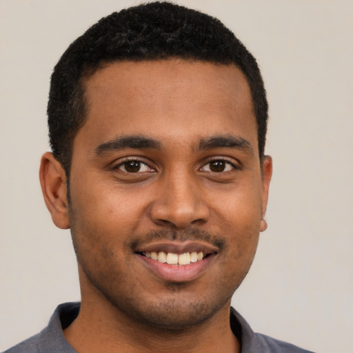 Joyful black young-adult male with short  black hair and brown eyes