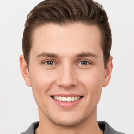 Joyful white young-adult male with short  brown hair and grey eyes