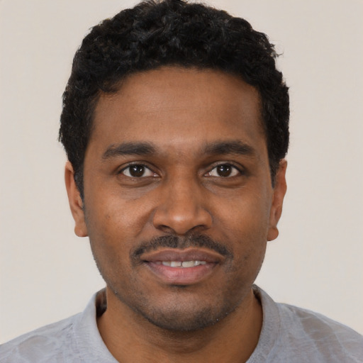 Joyful black young-adult male with short  black hair and brown eyes