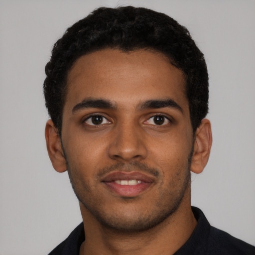 Joyful black young-adult male with short  black hair and brown eyes