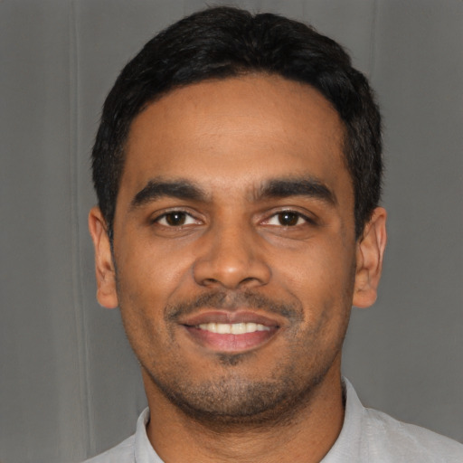 Joyful black young-adult male with short  black hair and brown eyes