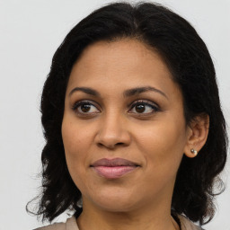 Joyful latino adult female with medium  brown hair and brown eyes