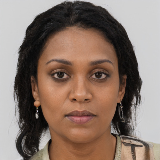 Joyful black young-adult female with long  brown hair and brown eyes