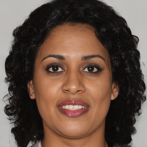 Joyful black young-adult female with long  brown hair and brown eyes