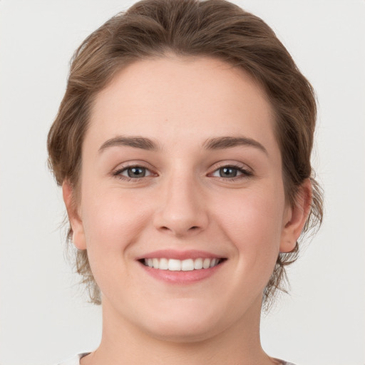 Joyful white young-adult female with medium  brown hair and grey eyes