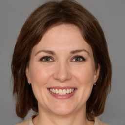 Joyful white adult female with medium  brown hair and grey eyes