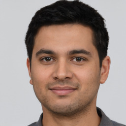 Joyful latino young-adult male with short  black hair and brown eyes