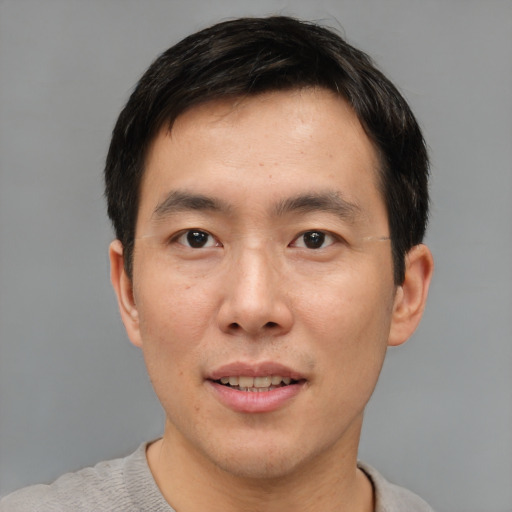 Joyful asian young-adult male with short  brown hair and brown eyes