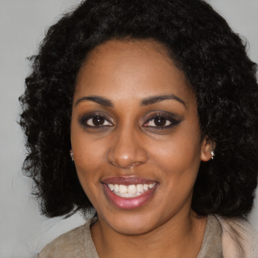 Joyful black young-adult female with long  black hair and brown eyes
