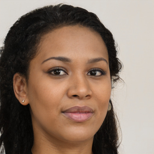 Joyful black young-adult female with long  brown hair and brown eyes