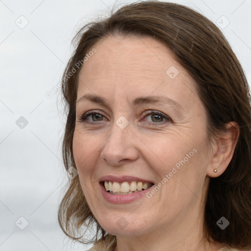 Joyful white adult female with long  brown hair and grey eyes