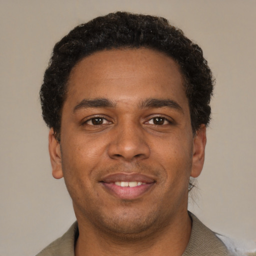 Joyful black young-adult male with short  brown hair and brown eyes