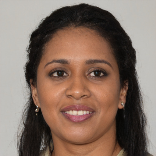 Joyful black young-adult female with long  brown hair and brown eyes