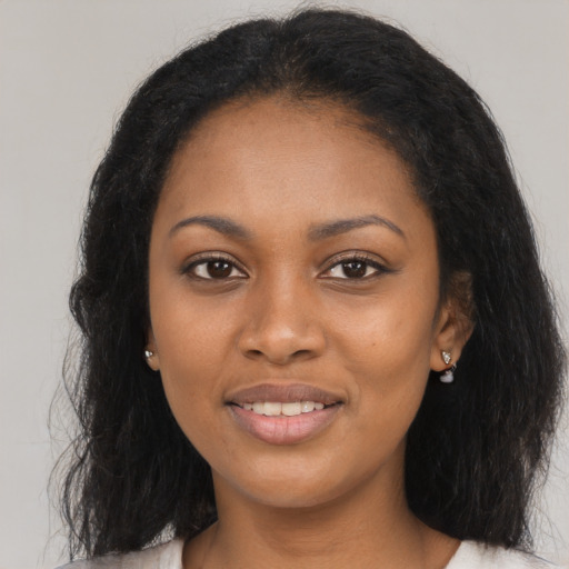 Joyful black young-adult female with long  brown hair and brown eyes