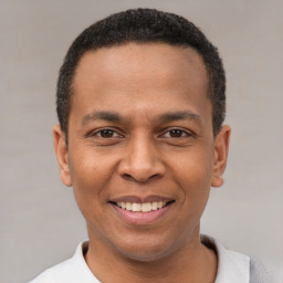 Joyful latino young-adult male with short  black hair and brown eyes