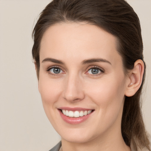 Joyful white young-adult female with medium  brown hair and grey eyes