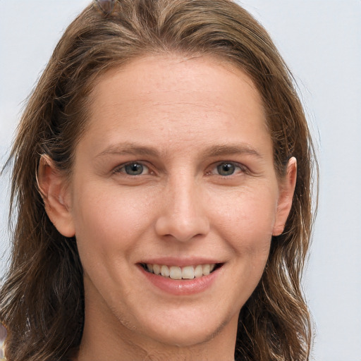 Joyful white young-adult female with long  brown hair and grey eyes