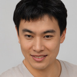 Joyful asian young-adult male with short  brown hair and brown eyes